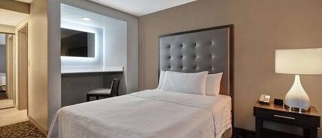 A hotel room with a large bed, a bedside table with a lamp, a modern headboard, and a wall-mounted TV.