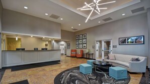 A hotel lobby with a reception desk, seating area, and framed pictures on the walls. - Homewood Suites by Hilton Edgewater (Edgewater)
