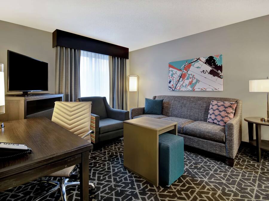 A hotel room with a TV, a desk, a sofa, and a coffee table.
