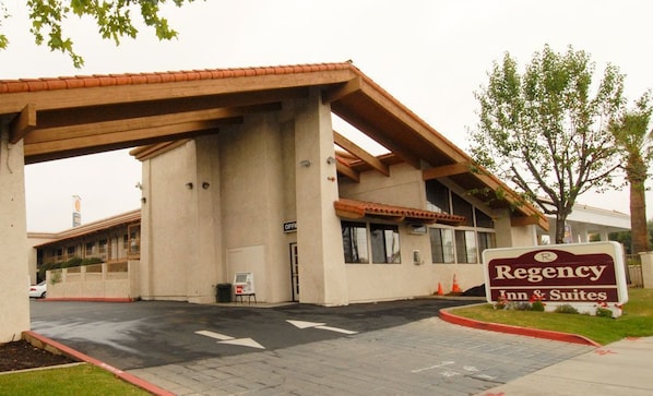 A Regency Inn & Suites with a covered parking area, a signboard, and a building entrance.