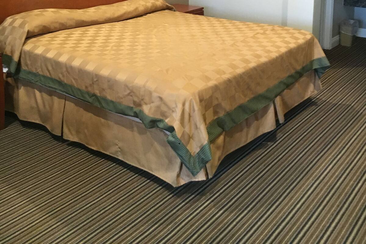Ein Hotelzimmer mit einem Bett, einem gerahmten Bild an der Wand und einer Tür zu einem Badezimmer.