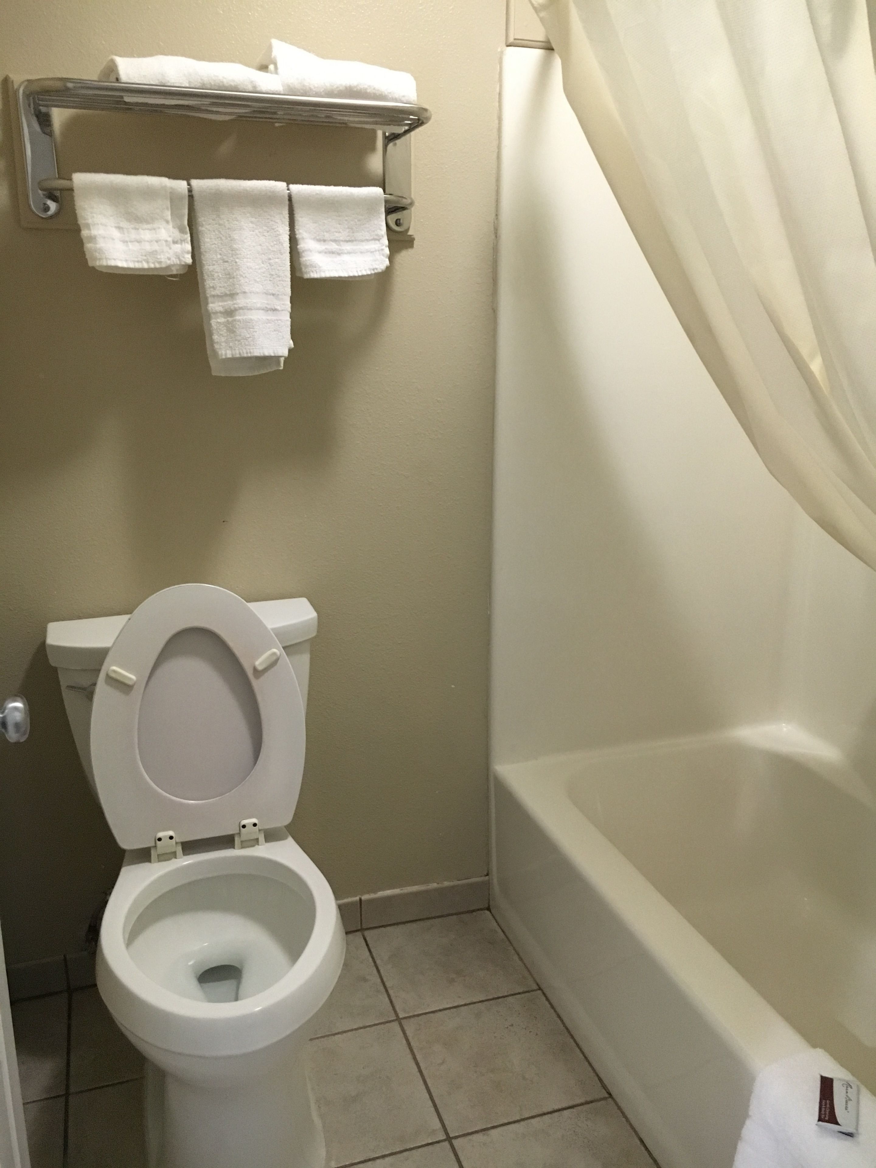 Un baño con inodoro, bañera y toallero con toallas.