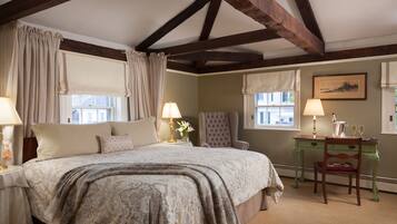 A bedroom with a large bed, two bedside tables with lamps, a green desk with a chair, and a framed picture on the wall.