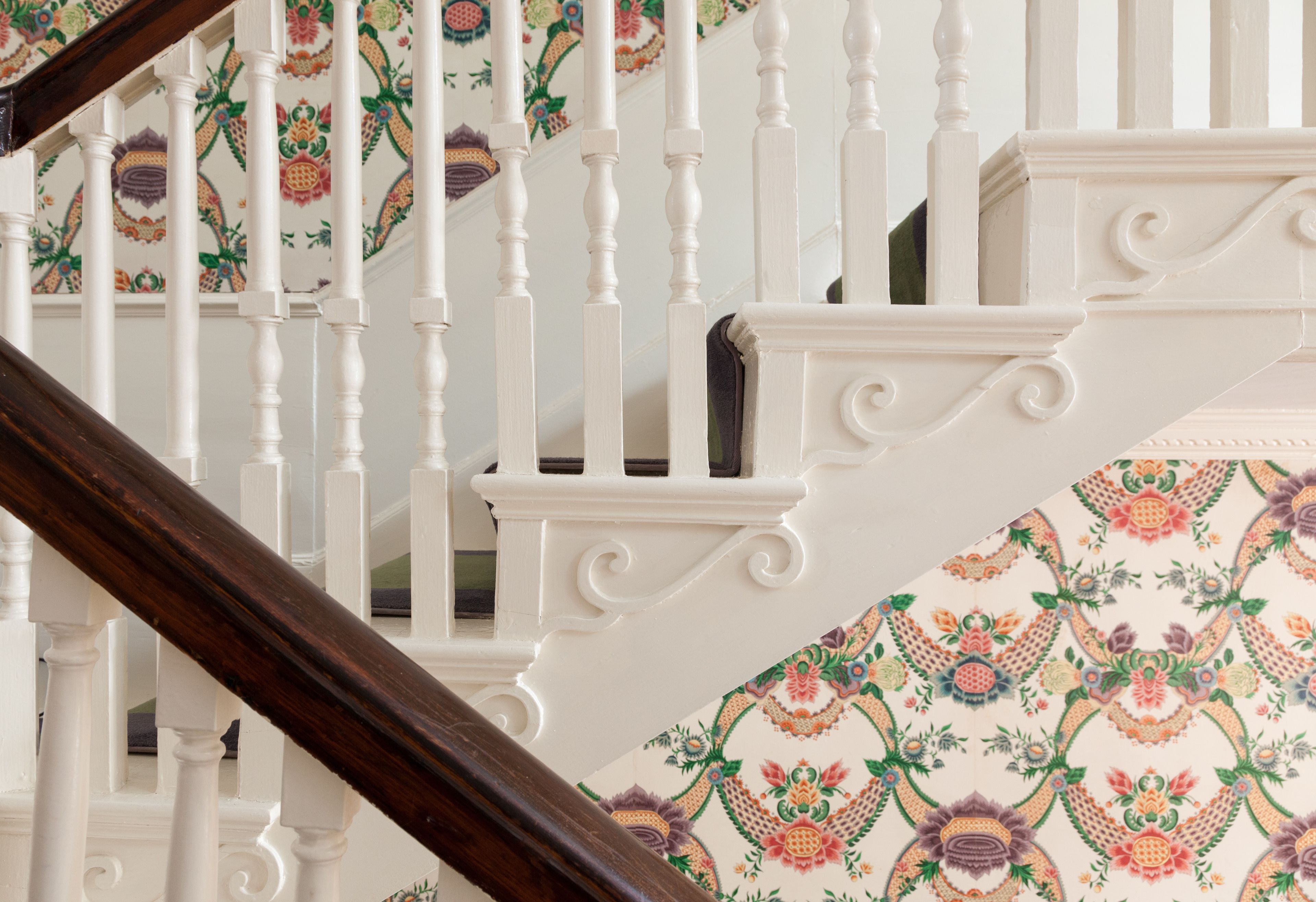 Un escalier avec des balustrades blanches et un papier peint à motifs.