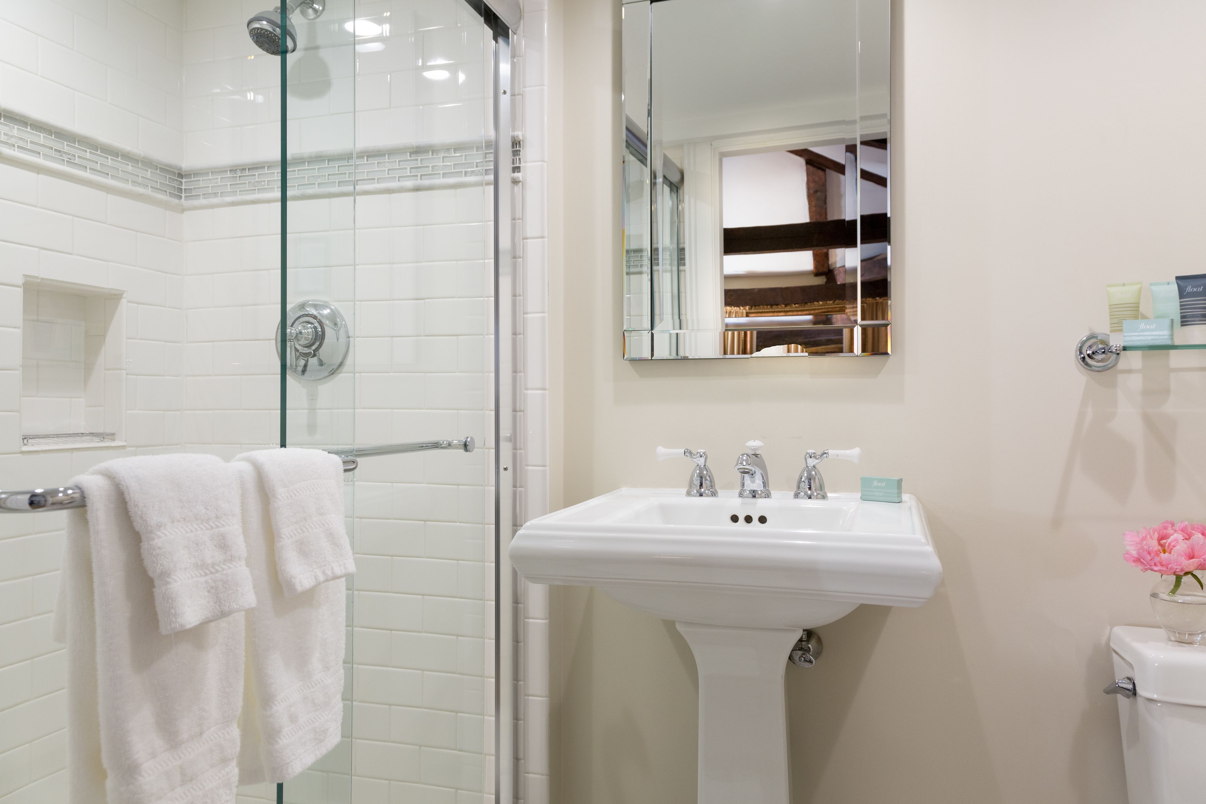 Un baño con ducha de vidrio, un lavabo blanco y un inodoro.