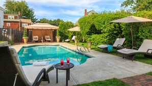 A backyard with a swimming pool, lounge chairs, and umbrellas. - Harbor Light Inn (Marblehead)