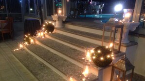 Una escalera con velas y faroles que lleva a una zona de piscina.