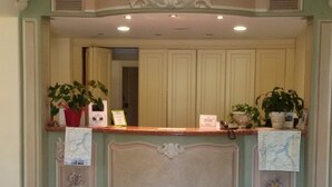 Un área de recepción con mostrador, dos sillas y elementos decorativos.