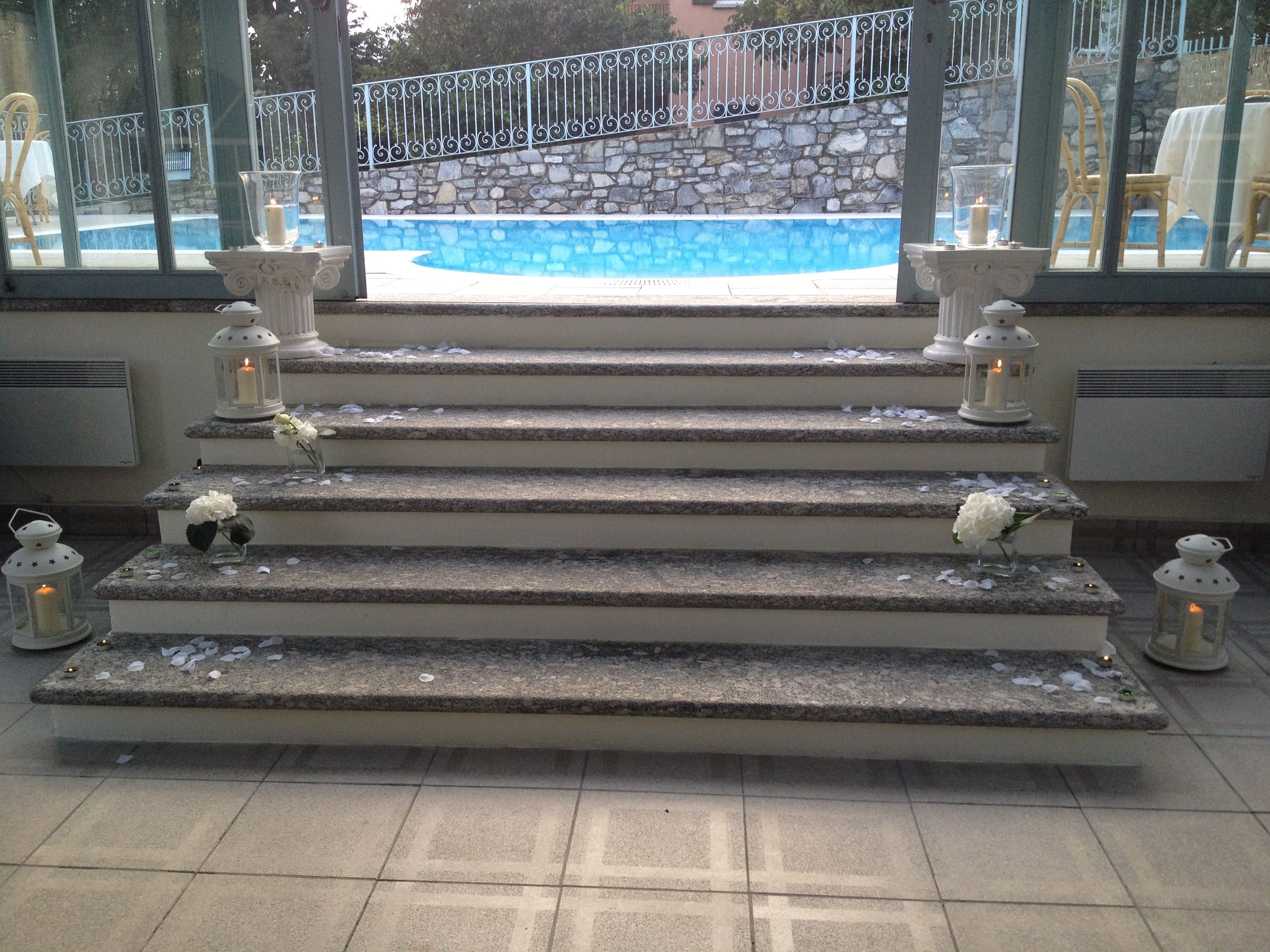 Un escalier en pierre menant à une zone abritant une piscine, avec des lanternes et des fleurs disposées sur chaque marche.