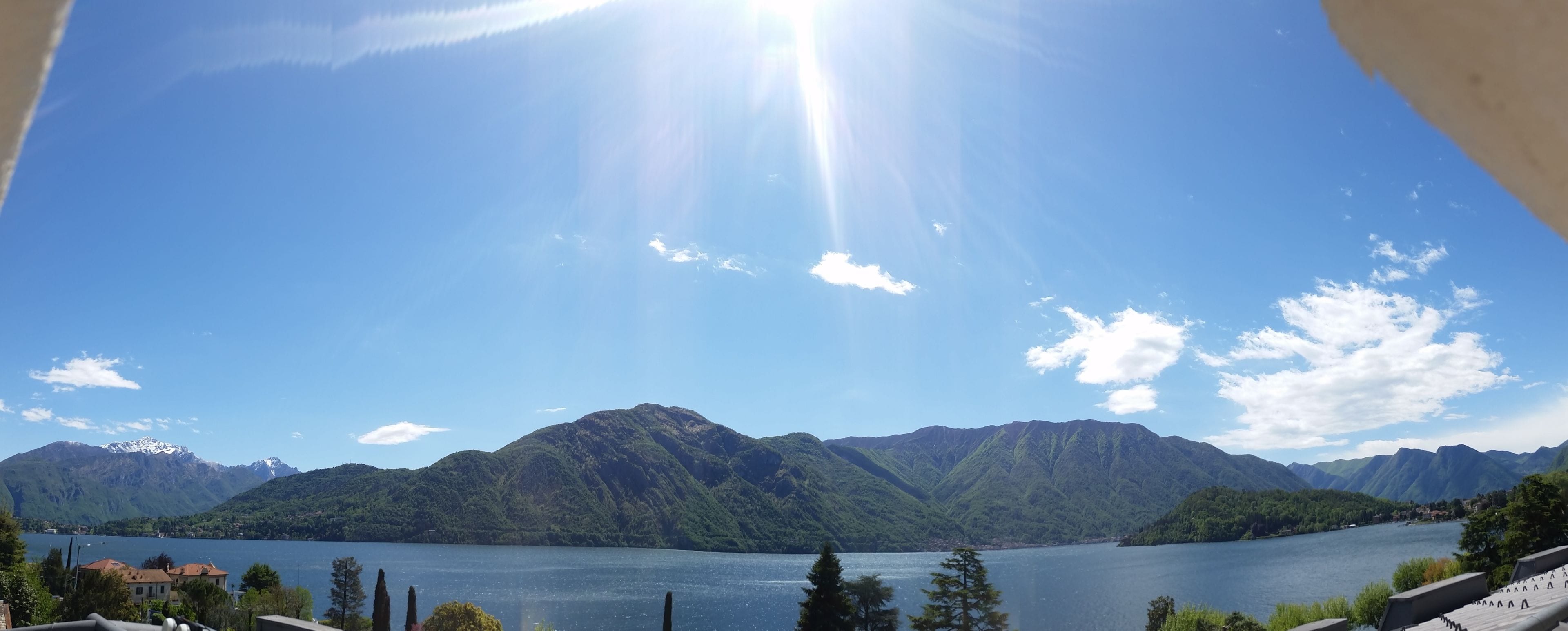 Une vue panoramique d’un lac entouré de montagnes, sous un ciel dégagé.