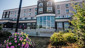 A hotel with a prominent 'PRESTIGE' sign, large windows, and a stone facade. - Prestige Treasure Cove Resort (Prince George)