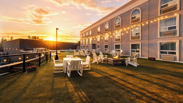 A hotel courtyard with outdoor seating, a fire pit, and a large building with arched windows. - Prestige Treasure Cove Resort (Prince George)