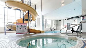 An indoor swimming pool with a waterslide, tiled floor, and clear pool area. - Prestige Treasure Cove Resort (Prince George)