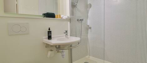 Un baño moderno con lavamanos blanco, inodoro y cabina de ducha.