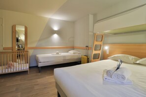 A hotel room with a large bed, a smaller bed, a crib, a mirror, and a wall-mounted light fixture. - Hôtel ibis budget Aix-les-Bains Nord (Gresy-sur-Aix)