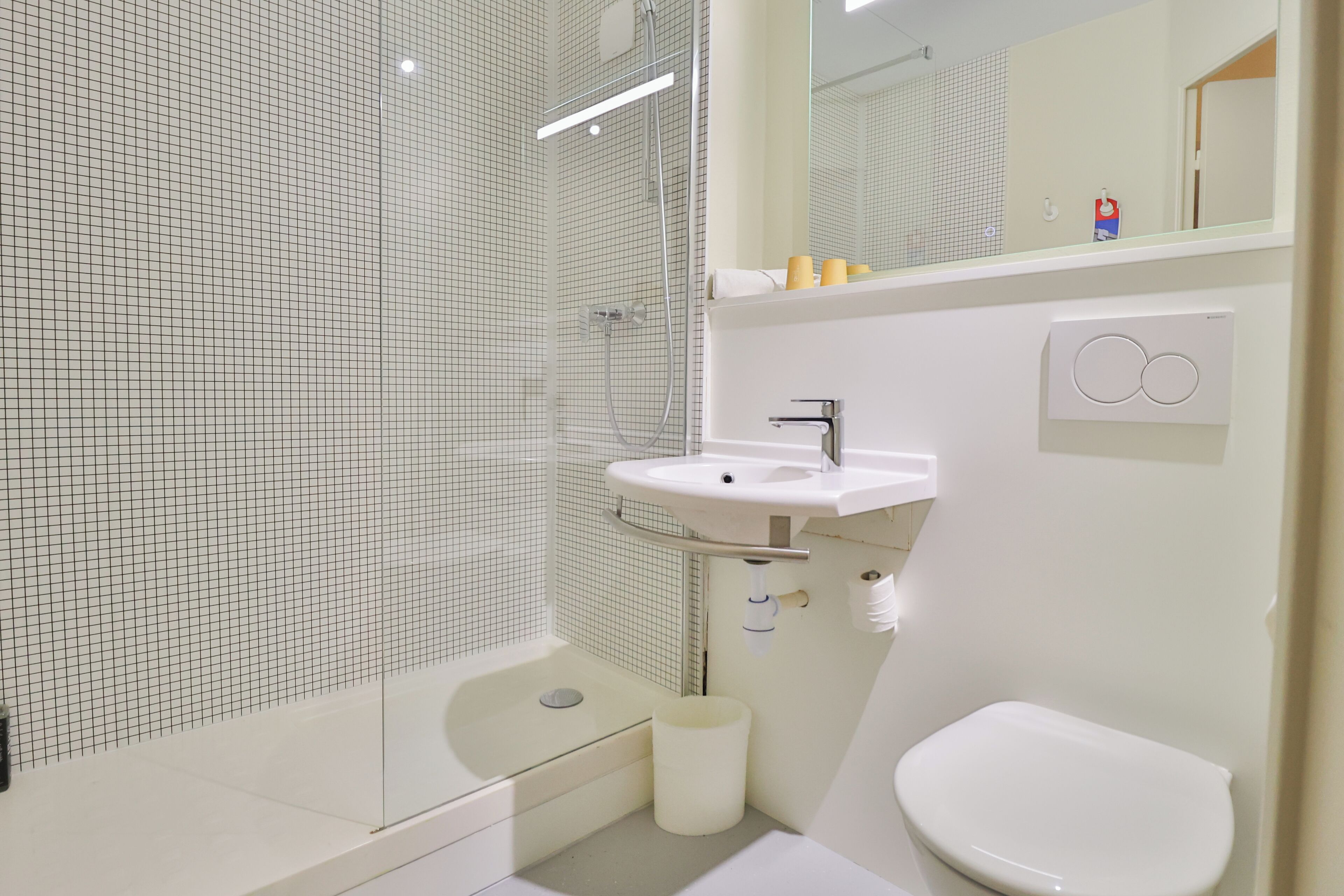 A modern bathroom with a glass-enclosed shower, a white sink, and a toilet.