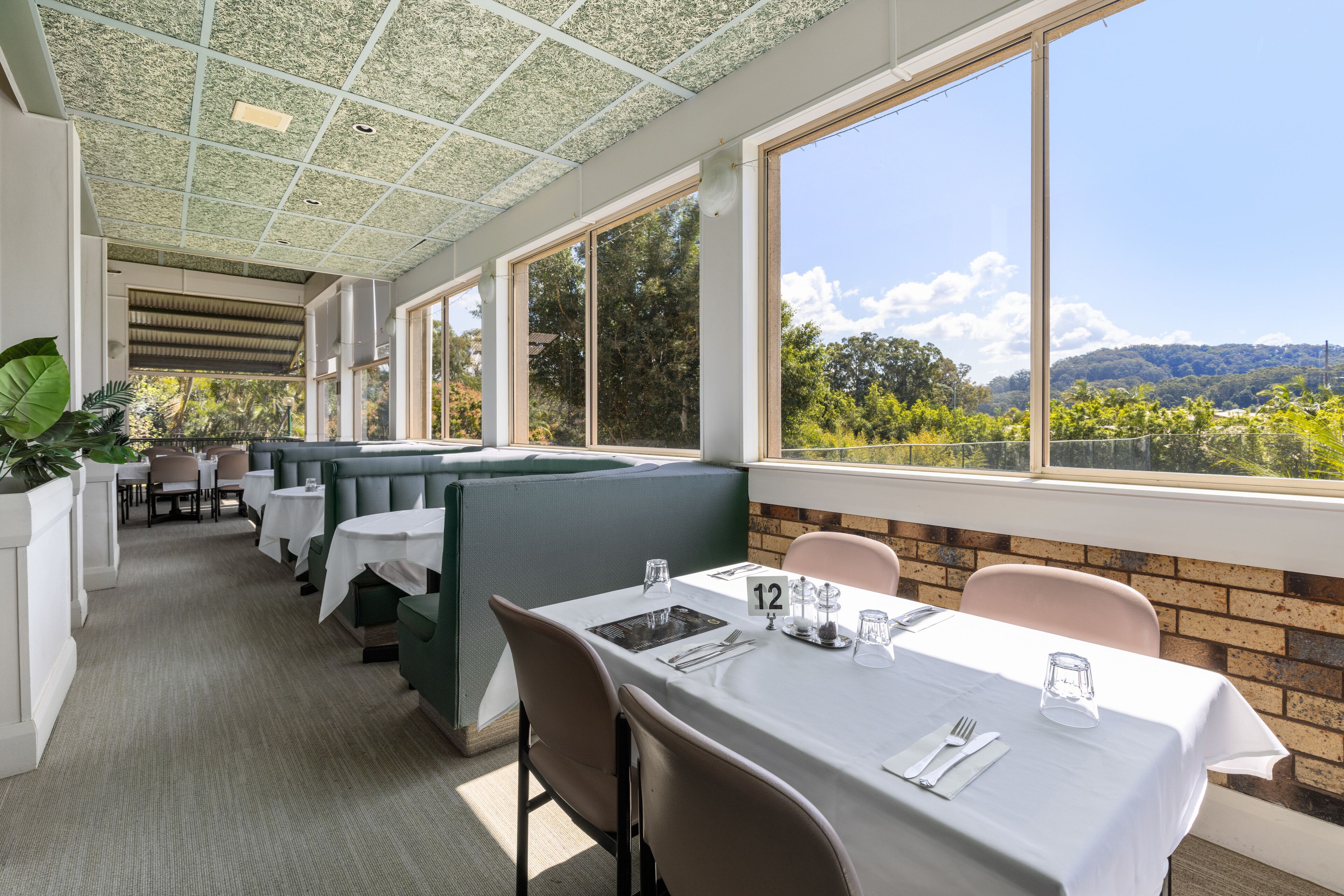 Un restaurante con terraza, amplios ventanales y vistas al paisaje.