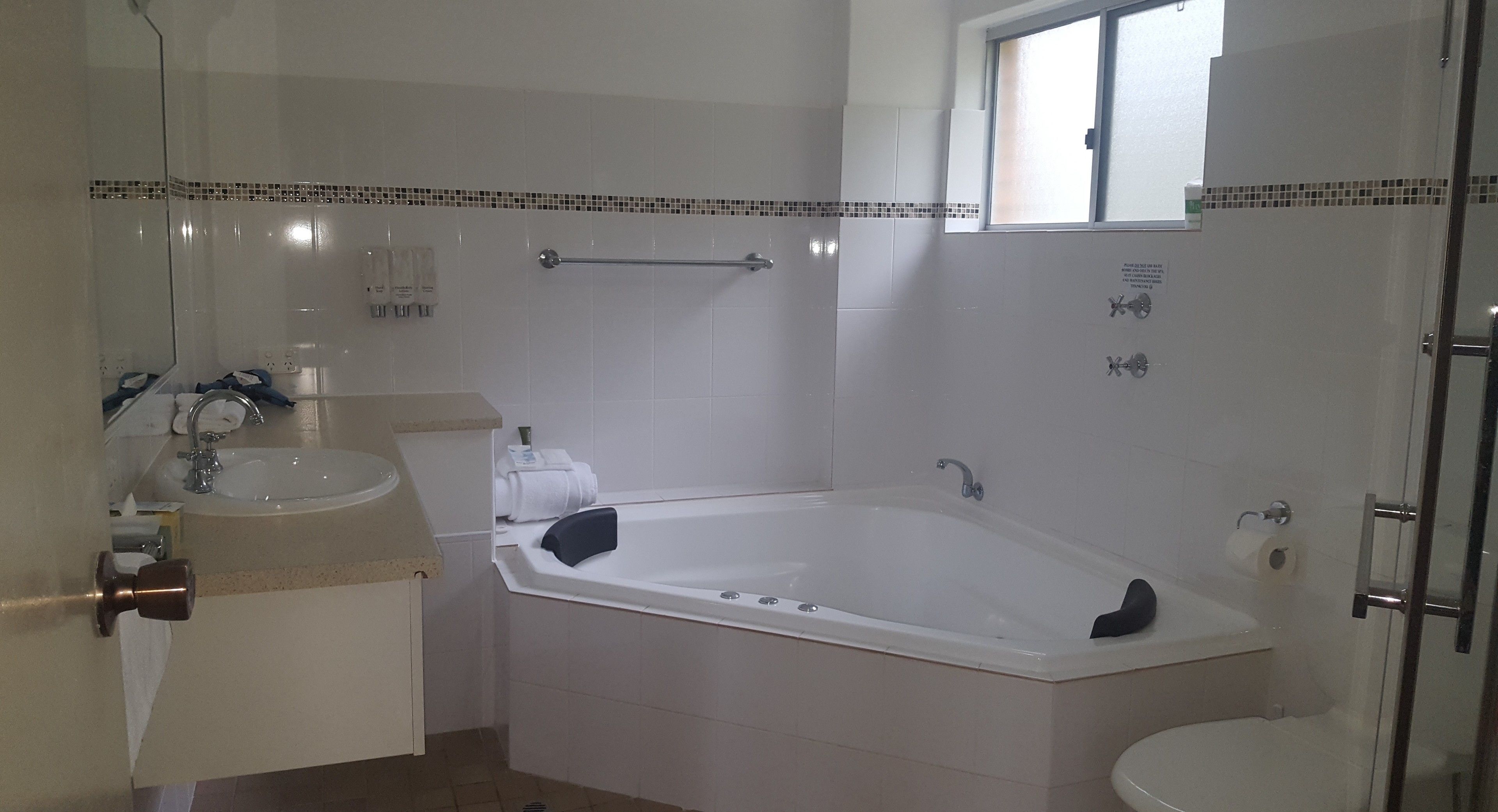 A bathroom with a bathtub, a sink, a toilet, and a window.