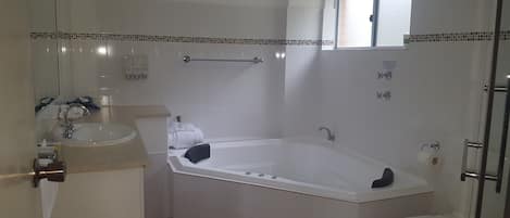 A bathroom with a bathtub, a sink, a toilet, and a window.