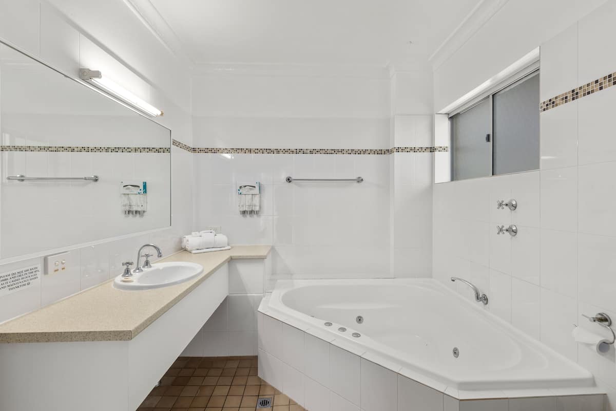 A modern bathroom with a large bathtub, a sink, and a mirror.