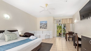 A hotel room with a bed, a desk, a chair, a TV, and a bathroom.