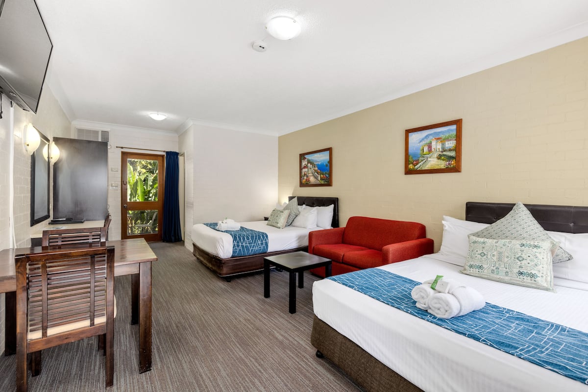 A hotel room with two beds, a TV, a desk, and a chair.