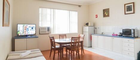 Um espaço compacto com área de refeições, cozinha compacta e uma cama.