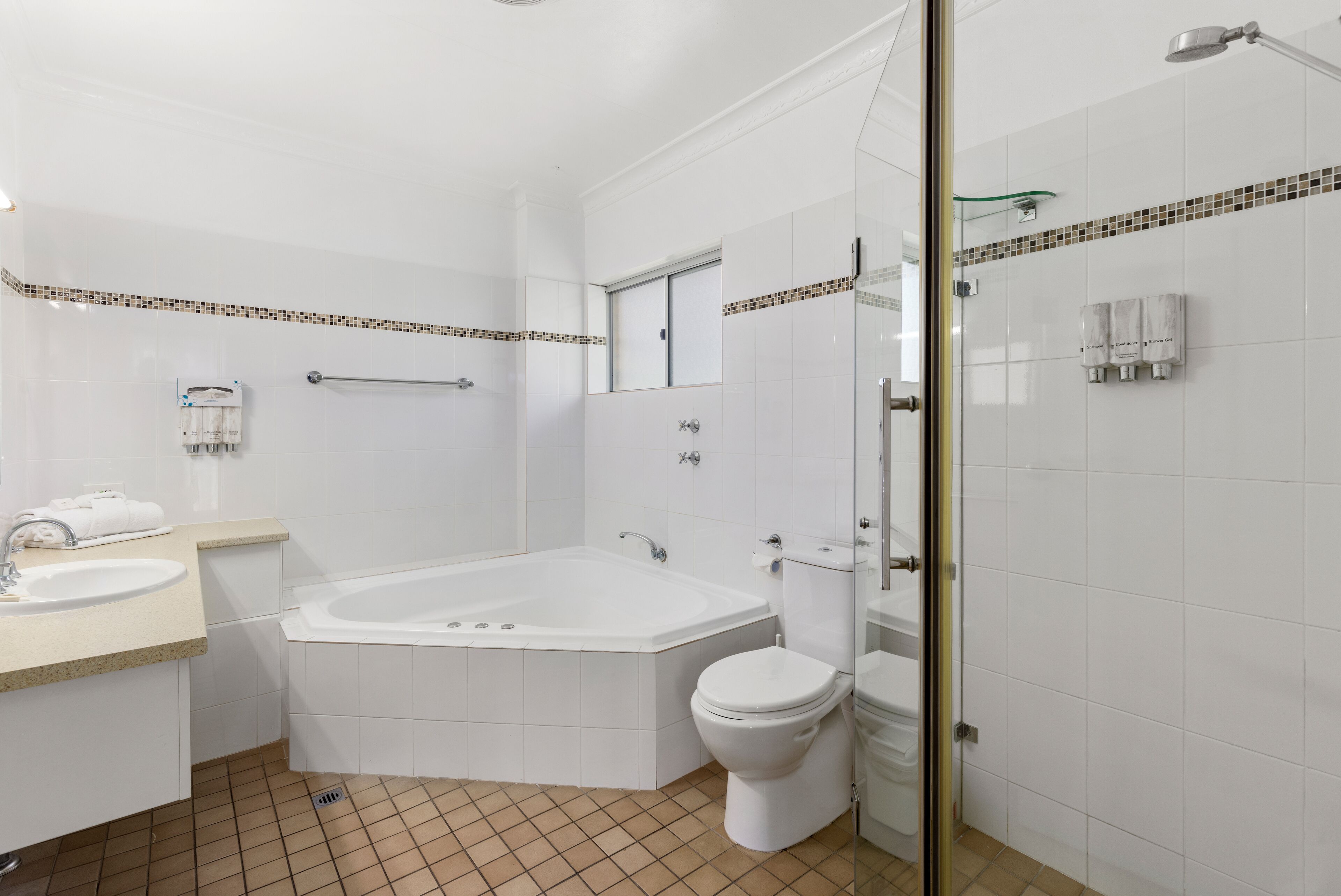 A modern bathroom with a bathtub, toilet, and glass shower enclosure.