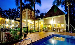 A hotel with a swimming pool, outdoor seating, and a brick structure.