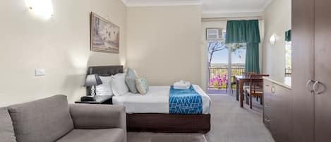 Una habitación de hotel con cama, sofá, escritorio y vistas al exterior.