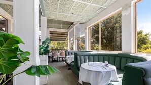 A restaurant with green booths, white tables, and a ceiling with a patterned design.