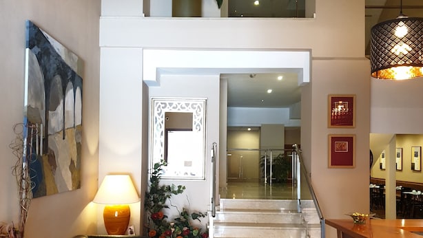 A spacious living area with a staircase leading to an upper floor, a modern sofa, a potted plant, and a dining area with a chandelier. - Hotel Suite Camarena (Teruel)