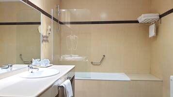 Un baño moderno con ducha envuelta en vidrio, bañera y tocador con lavabo y espejo.