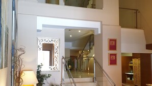 A spacious lobby with a staircase leading to an upper floor, a seating area with a sofa and a table, and a potted plant. - Hotel Suite Camarena (Teruel)