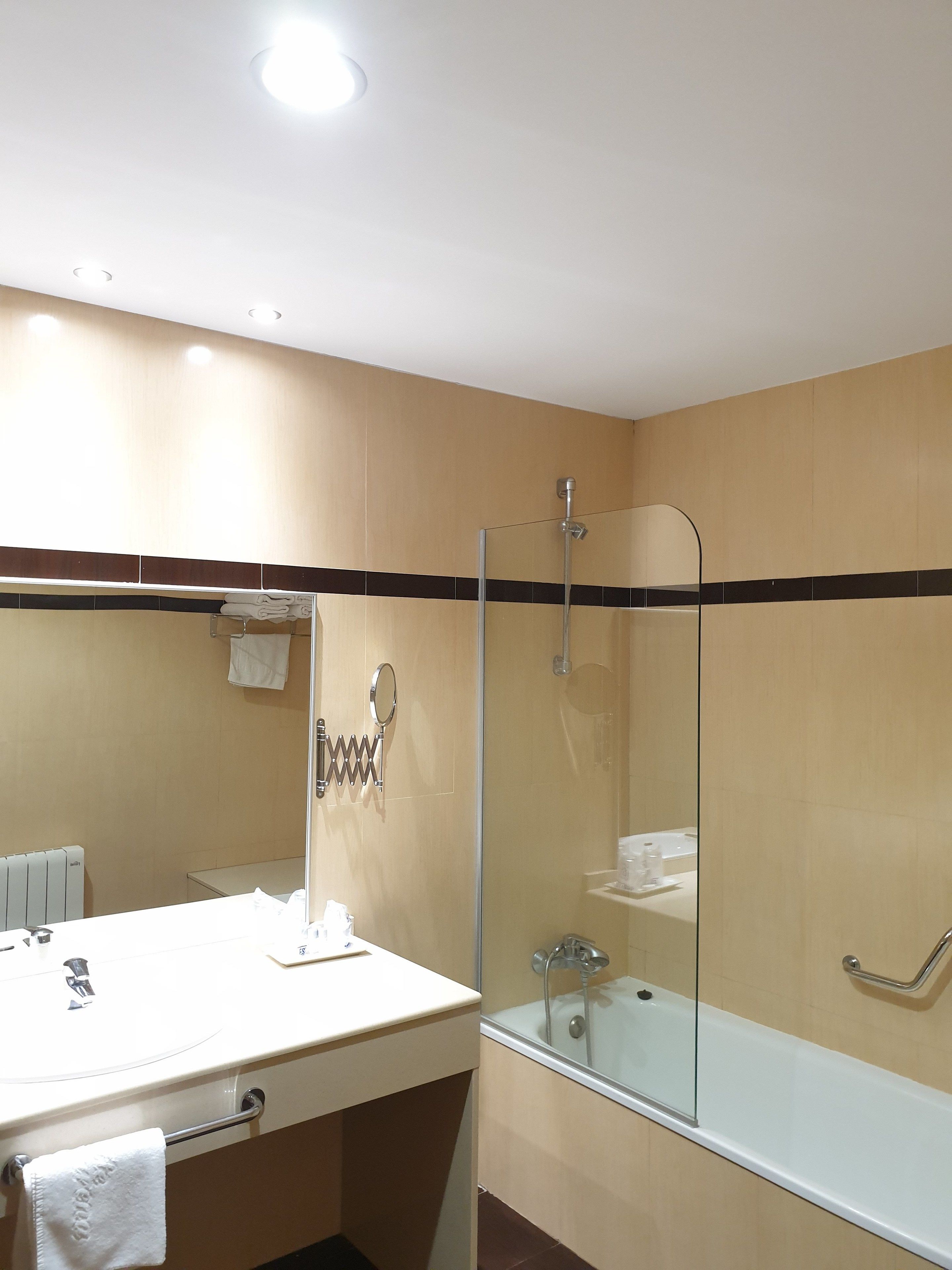 Un baño con ducha envuelta en vidrio, un lavabo blanco y un espejo.