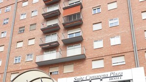 A hotel entrance with a sign for 'Suite Camarena Plaza Hotel'. There are flags, a no parking sign, and a pedestrian pathway leading to the entrance. - Hotel Suite Camarena (Teruel)