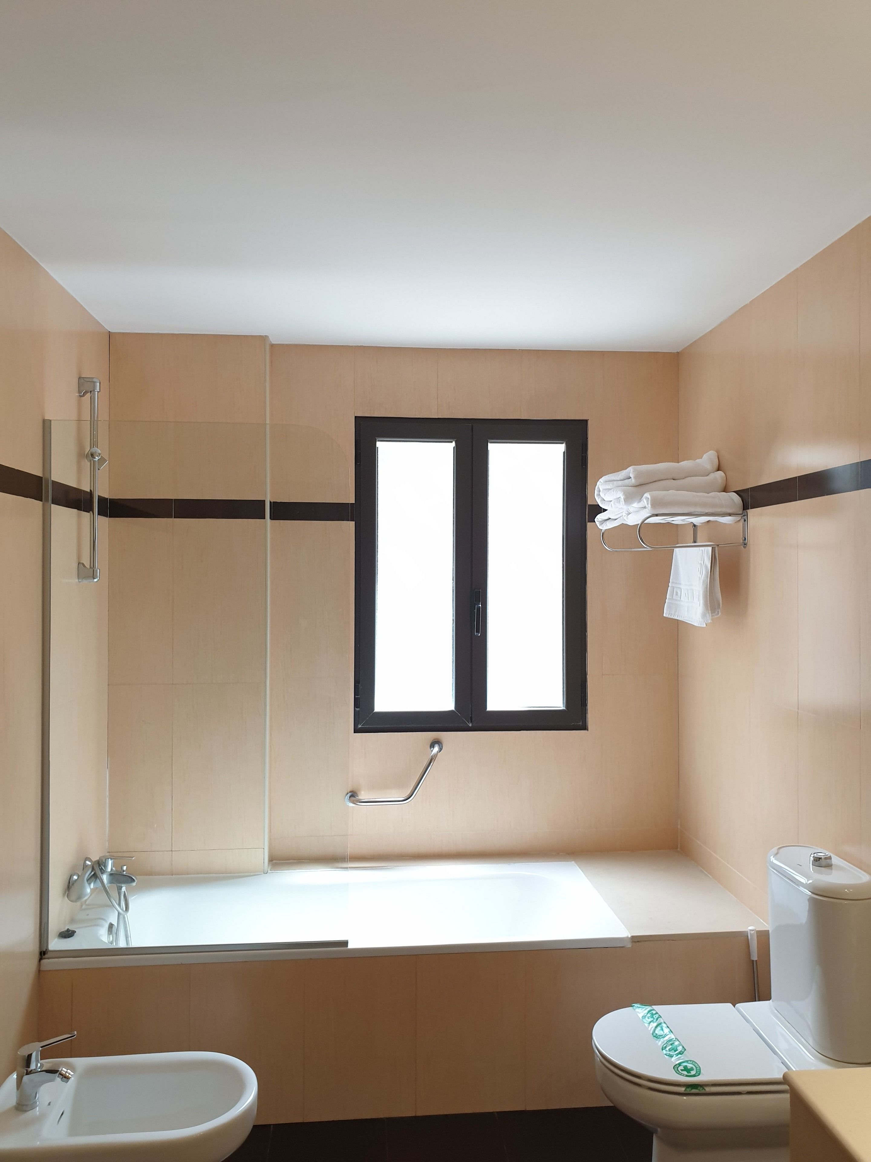 A bathroom with a bathtub, toilet, sink, and a window.