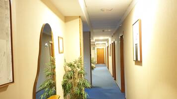 A hotel hallway with a blue carpet, wooden doors, and framed pictures on the walls.
