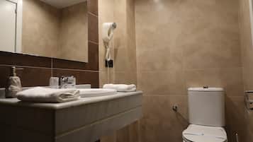 Un baño con lavamanos, dispensador de toallas y un inodoro.
