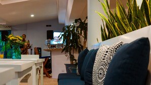 A modern living room with a sofa set, a dining table, and a TV in the background.