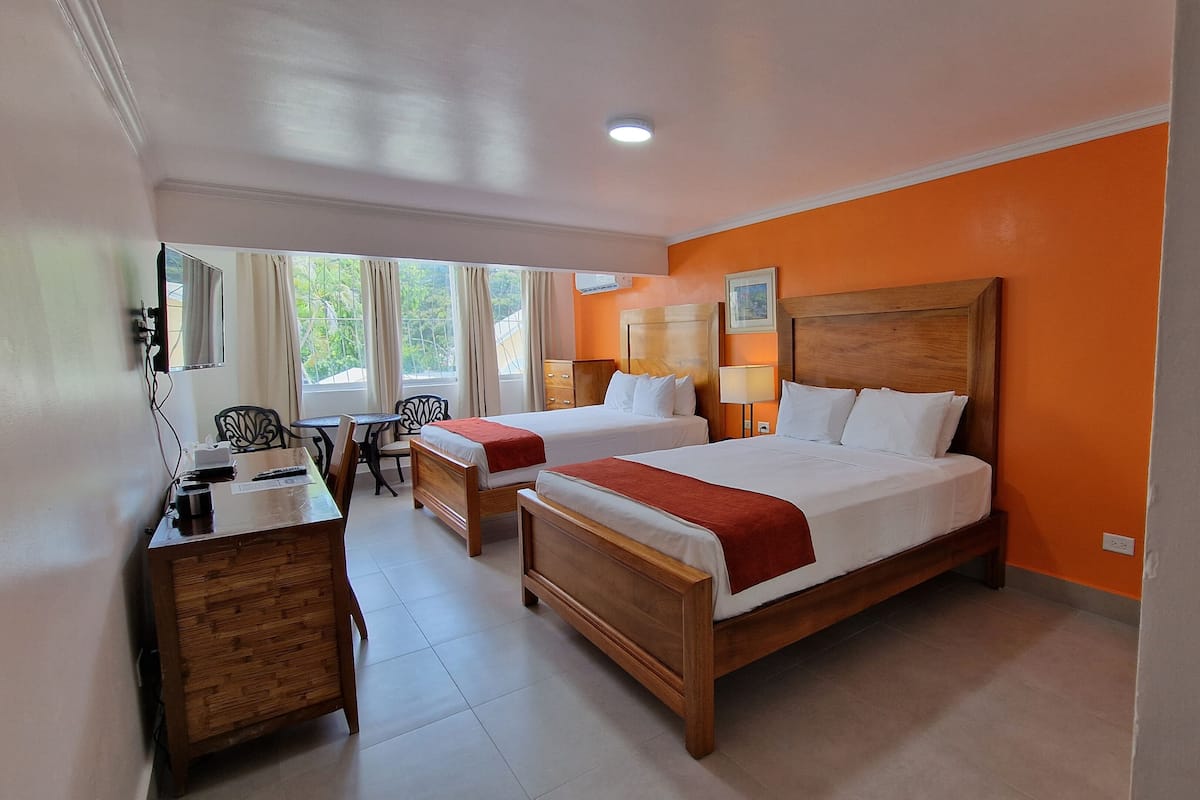 A hotel room with two beds, a desk, and a chair.