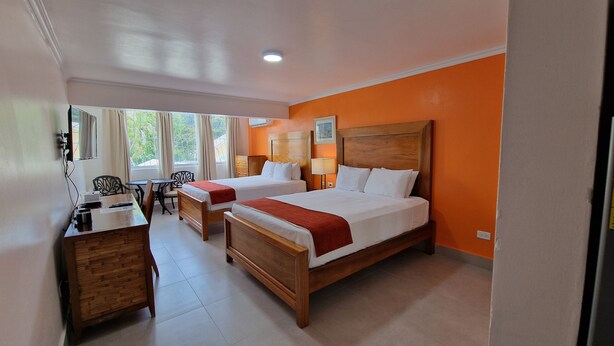 A hotel room with two beds, a desk, and a chair.