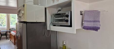 Cocina compacta con refrigerador, tostadora y lavamanos.