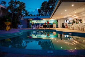 A pool area with lounge chairs and a bar area with a mural. - Pirate's Inn (Marine Gardens)