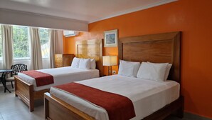 A hotel room with two beds, a desk, a chair, and a window with curtains.