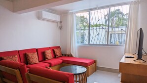 A living room with a red sofa, a round coffee table, and a TV on a wooden stand.