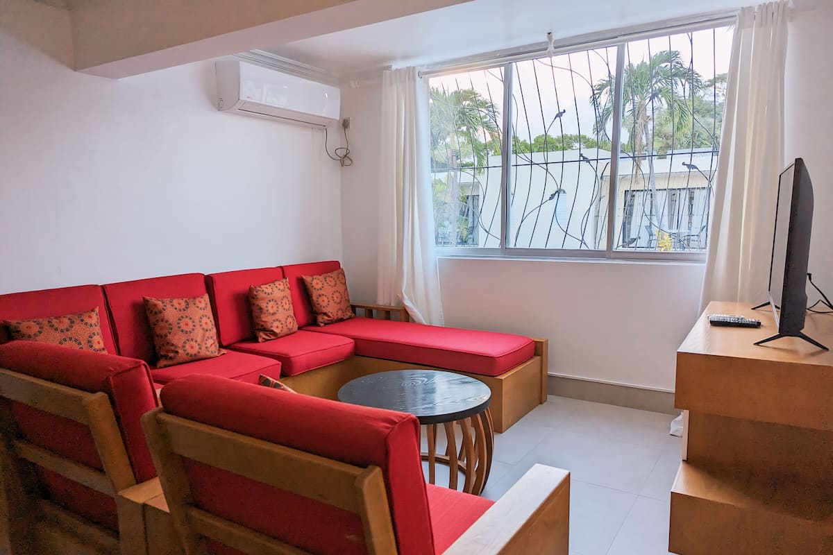 A living room with a red sofa, a round coffee table, and a TV on a wooden stand.
