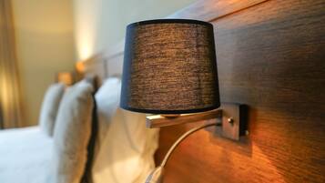 Een close-up van een wandlamp met een gestructureerde kap, een metalen arm en een schakelaar.