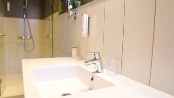 Une salle de bain avec un lavabo blanc, un robinet moderne et une douche à parois de verre.
