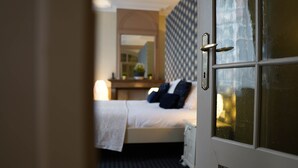 Une chambre d’hôtel avec un lit, une table de chevet, un miroir et une fenêtre.
